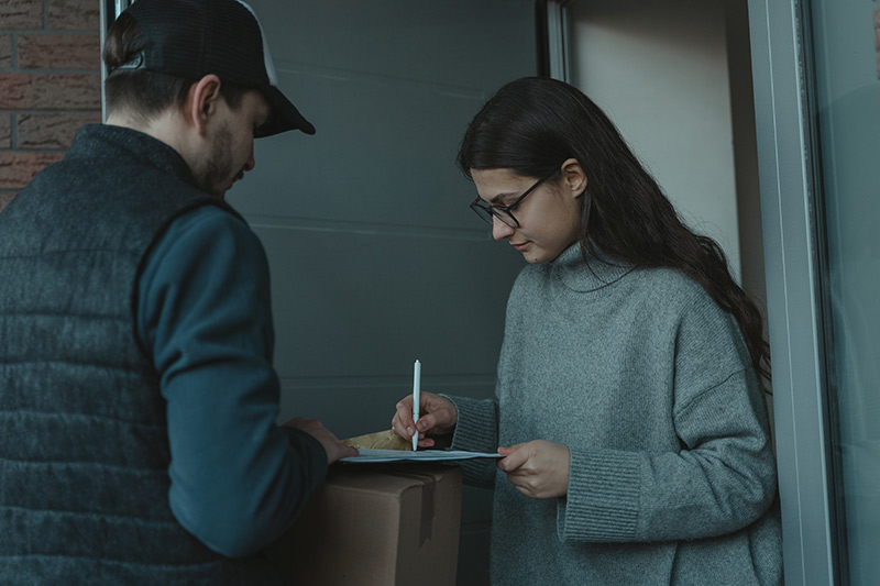 Woman in blue sweater holding pen and paper