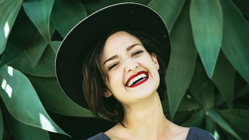 Woman smiling in front of green plants